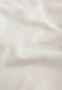 Licht beige stof met een gladde, zachte textuur; heeft een subtiele glans en lichte kreukels, die een lichte en delicate uitstraling laten zien.