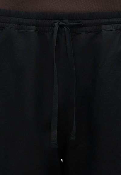 Μαύρη ελαστική μέση με δεμένο κορδόνι σε μαύρο καθημερινό παντελόνι ή σορτς.