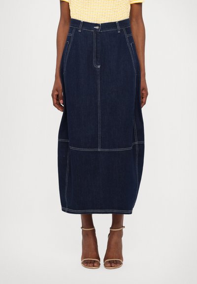 Mørkeblå denim midi-nederdel med hvid syning, høj talje, sidelommer og afslappet pasform, parret med nude sandaler.