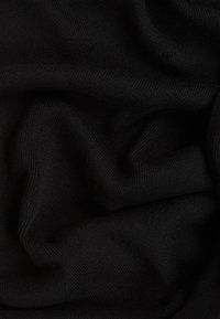 Tissu tricot noir au toucher doux, présentant une apparence lisse et fluide avec des nervures horizontales subtiles. Froissé et superposé.