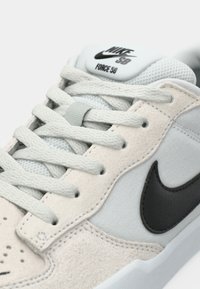 Nike SB Force 58 tenisice imaju gornji dio od svijetlosive suede kože, crni kožni swoosh i teksturirane vezice; minimalistički dizajn s podstavljenim jezikom.