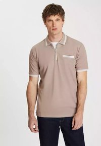 Brązowa koszulka polo z krótkim zamkiem, z białymi akcentami na kołnierzu i mankietach, oraz niewielką przednią kieszenią z wzorem w paski.
