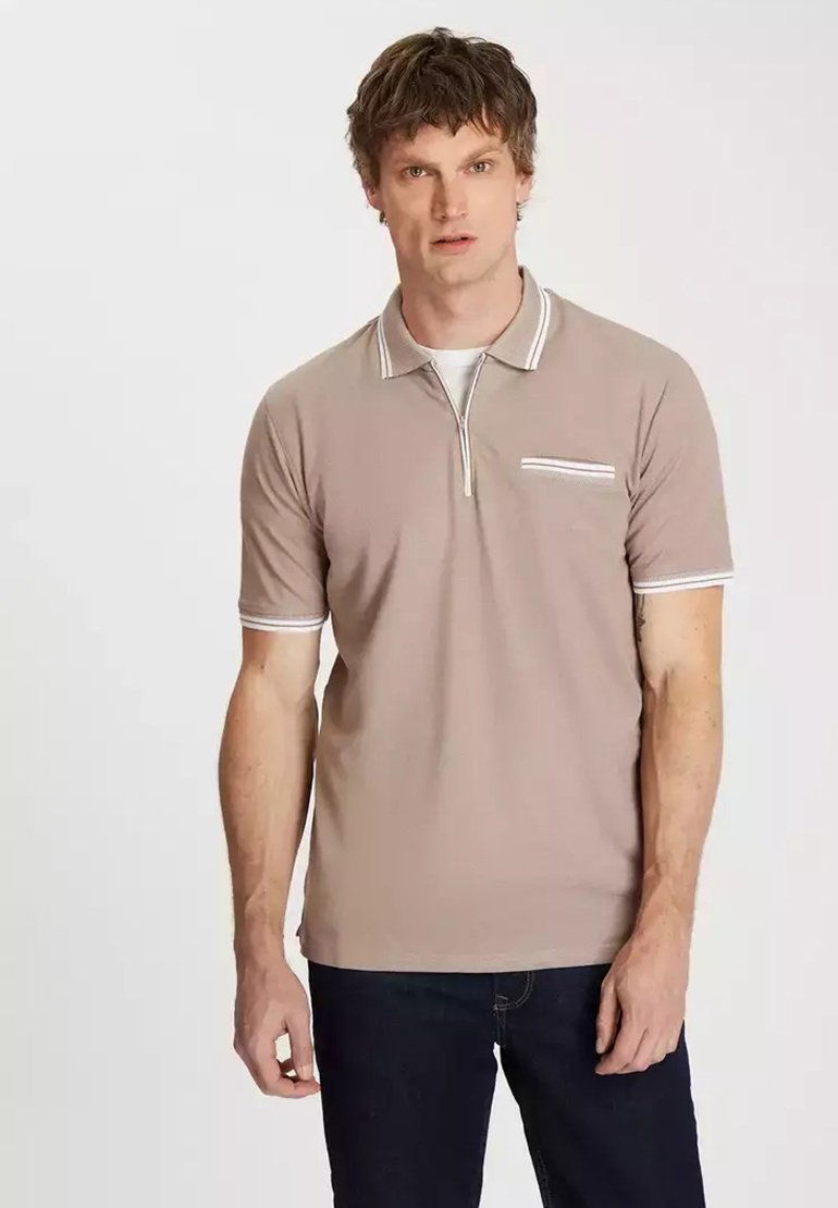 Brązowa koszulka polo z krótkim zamkiem, z białymi akcentami na kołnierzu i mankietach, oraz niewielką przednią kieszenią z wzorem w paski.