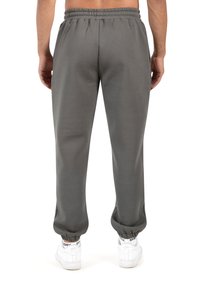 Pantalones deportivos grises hechos de material suave, con una cintura y puños elásticos, un ajuste relajado y sin bolsillos visibles.