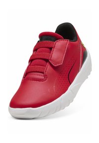 Czerwony syntetyczny sneaker z teksturowaną cholewką, wyściełanym kołnierzem, regulowanym paskiem, białą gumową podeszwą oraz perforacjami z boku dla lepszej wentylacji.