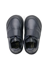 Zapatos de cuero negro con puntera redondeada, correa de velcro y suela texturizada. Superficie lisa con acentos mínimos y marca interior.