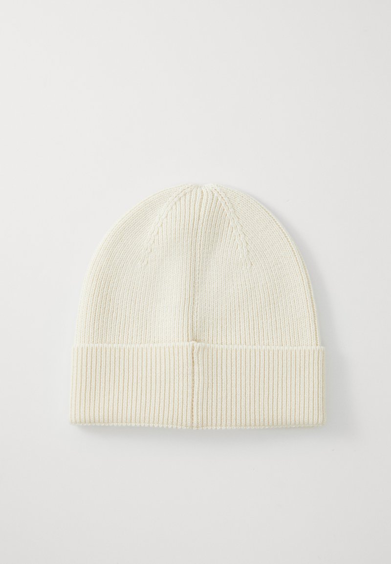 Bonnet en tricot crème avec une texture côtelée, doté d'un revers et d'une partie supérieure lisse avec des détails de couture discrets.