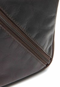 Borsa in pelle marrone con cucitura diagonale, finitura testurizzata e zip a contrasto lungo un lato per una chiusura sicura.