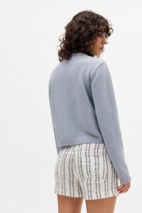Light blue, cropped sweater in soft fabric with ribbed hem, paired with white and blue striped shorts featuring a textured finish and pockets.