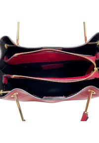 Borsa a tracolla in pelle rossa con dettagli neri, dotata di due scomparti con zip e hardware dorato. Superfici lisce e testurizzate visibili.