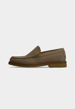 Pruun seemisnahast loafer õmblustega detaileeritult, madala kontsaga ja slip-on disainiga ühtlase helehall tausta peal.