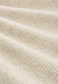 Teksturowana tkanina w miękkim beżu z delikatnymi skośnymi paskami. Materiał z mieszanki wełny, o ciepłym, przytulnym wyglądzie i gładkim wykończeniu.