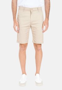 Shorts chino beige con risvolti, design a pantaloni piatti e tasche laterali. Realizzati in una morbida miscela di cotone per il massimo comfort.