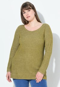 Olivgrüner Strickpullover mit gerippter Textur, langen Ärmeln und weitem Rundhalsausschnitt, kombiniert mit blauen Ripp-Jeans.