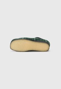 Pantofole di lana con una parte superiore in verde e nero texture e una suola beige morbida. Forma arrotondata e senza hardware o dettagli visibili.