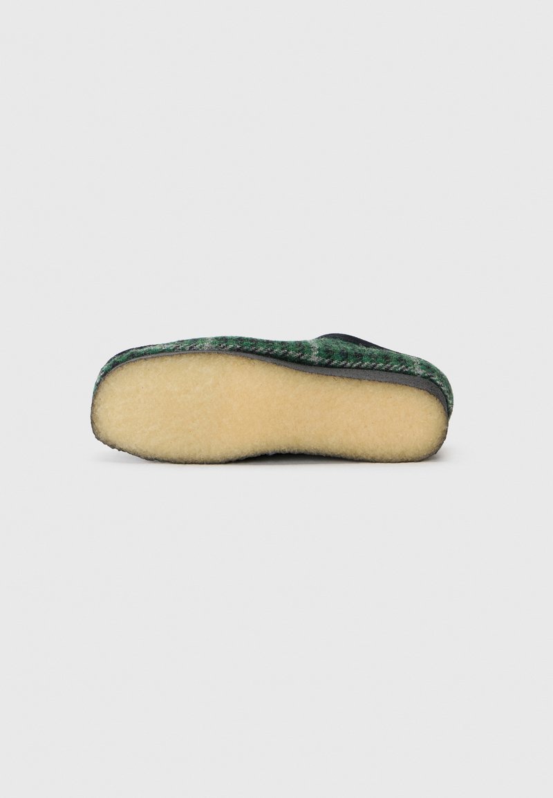 Wool slipper featuring a textured green and black upper with a soft beige sole. Rounded shape and no visible hardware or accents.