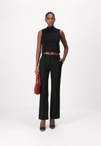 Must mustrakk tükk-särgid ja musta pinstripe laiad püksid, mida täiendavad punane käekott ja mustad terava ninaga kontsad.