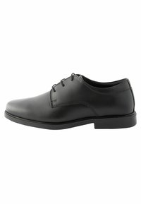 Chaussure de ville en cuir noir avec un bout rond, un avant lisse, six œillets et une semelle en caoutchouc à profil bas. Texture lisse avec des détails de couture discrets.