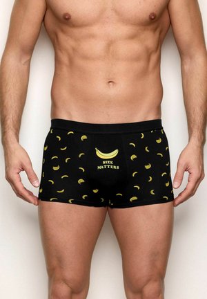Czarne bokserki z małymi żółtymi wzorami bananów oraz dużą grafiką banana z napisem „ROZMIAR MA ZNACZENIE” na przednim środku.