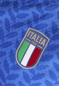 Blauw sportshirt met een textuurpatroon. Voorzien van een rechthoekige badge met "ITALIA" en de Italiaanse vlag in groen, wit en rood.