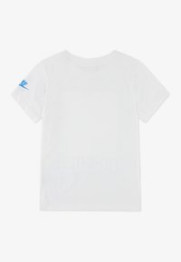 Hvit t-skjorte med korte ermer laget av bomull, med en blå Nike-logo på venstre erme og en ensfarget rygg med rund hals.