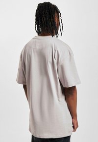 Light gray oversized t-shirt with short sleeves, made of soft cotton. Features a rounded neckline and a smooth texture. Simple design.