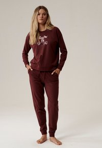 Burgundowy zestaw odzieży domowej składający się z długiego rękawa z nadrukowanym tekstem oraz dopasowanych joggerów. Wykonany z miękkiego i wygodnego materiału.