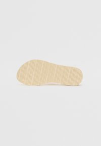 Gummisko sål i beige, med teksturerede vandrette riller og en rund tå. Glat finish med indgravering af mærkenavnet på hælen.