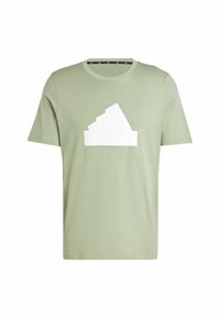 Camiseta de algodón verde con un prominente logo blanco de Adidas en el frente. Cuello redondo con una textura suave y mangas cortas.