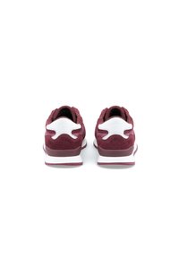 Red suede sneakers featuring a white heel accent and a cushioned sole. Rounded toe, textured upper, and padded collar.
