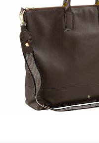 Sac fourre-tout en cuir marron avec une finition texturée, accents dorés et une bandoulière en tissu à rayures. Il possède des poignées doubles et une fermeture éclair.