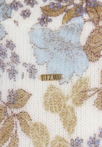 Gebreide stof met een bloemenpatroon in blauwe en bruine tinten, voorzien van een goudkleurig "BIZUU" logo label. Zachte textuur, lichte achtergrond.