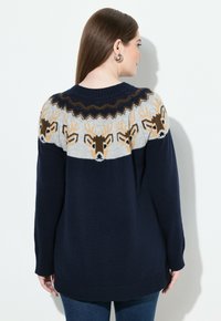 Maglione lavorato a maglia blu navy con un giromanica grigio decorato da un motivo di cervi e un design a chevron. Maniche lunghe e orlo a costine completano il look.