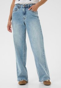 Lyseblå jeans med vide ben, høj talje, let falmet effekt og kontrastsyninger, med forlommer og knaplukning.