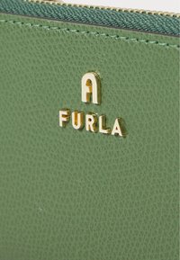 Portafoglio in pelle verde con finitura testurizzata, caratterizzato da un logo dorato "FURLA" e accessori metallici lungo la cerniera.