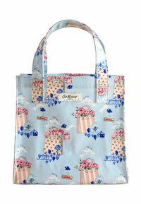 Bolsa de tela azul con patrones florales y de lunares, cuenta con asas cortas y una etiqueta con el logo. Diseño ligero y rectangular.