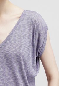 T-shirt viola a scollo a V con un motivo a righe orizzontali testurizzato. Tessuto morbido con maniche a cappuccio leggermente arrotolate e una vestibilità rilassata.