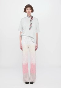 Light gray oversized t-shirt with a patterned neck detail, paired with gradient pink and beige zigzag patterned wide-leg pants.