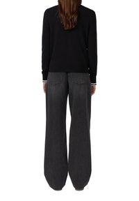 Un pull noir en tricot à manches longues, associé à un jean gris foncé à taille haute et jambes larges, doté de poches arrière et de détails de couture subtils.