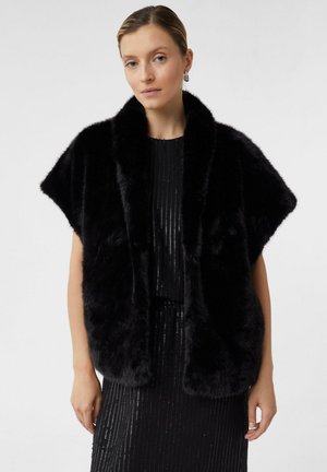 Czarny futrzany szal z krótkimi rękawami, o miękkiej strukturze i szerokim kołnierzu, noszony na dopasowanej czarnej sukience wyszywanej cekinami.