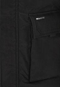 Černá látková bunda se zřetelným kapsou s klopou a logem. Hladká textura, čisté šití a minimalistický design.