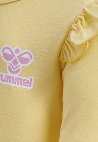 Geel katoenen top met een bijenprint in roze en wit, met ruffles op de mouwen voor extra textuur.
