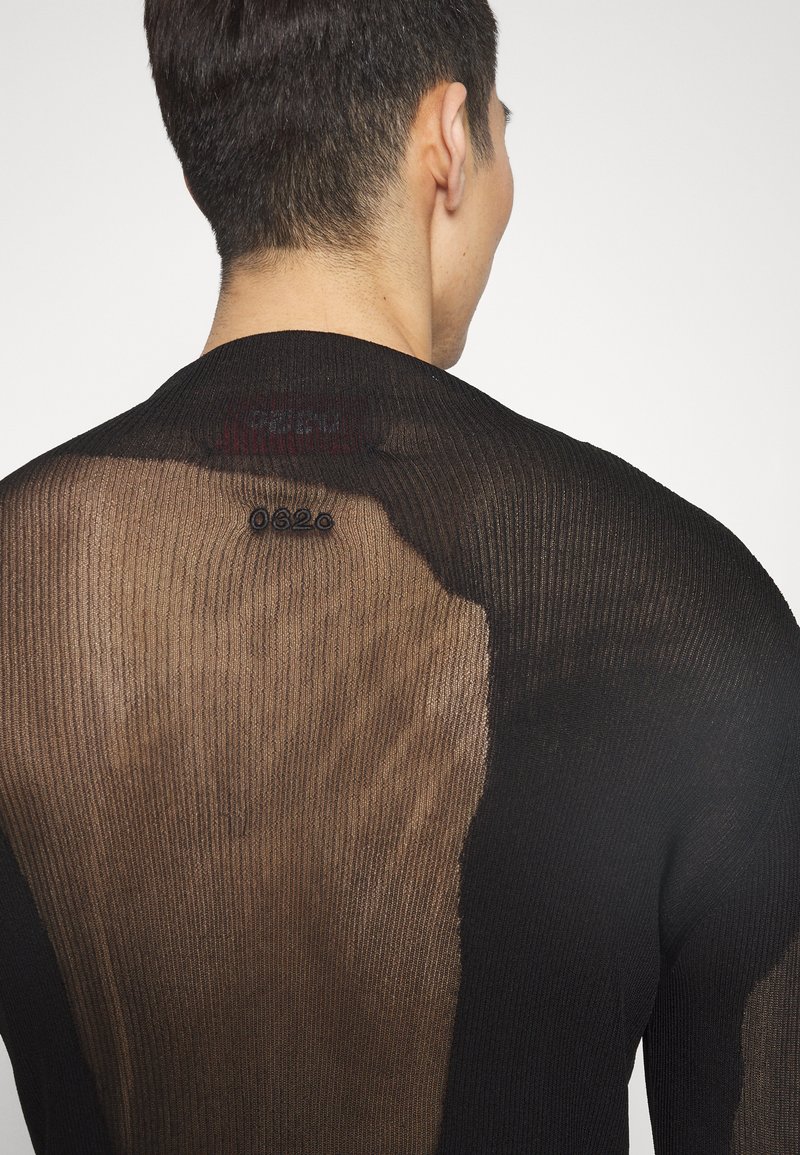 Maglione nero a maglia con una texture trasparente, caratterizzato da un motivo a coste e un pannello unico di colore marrone chiaro sulla schiena, vicino alla scollatura.