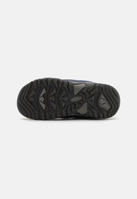 Schwarze Gummilaufsohle mit strukturiertem Gripp-Muster. Verfügt über multidirektionale Stollen und Rillen für bessere Traktion. Verstärktes Zehenkappendetail.