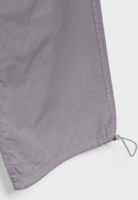 Tela de color púrpura claro con una textura suave, que presenta un dobladillo curvado y un detalle de ajuste con cordón y tope en la parte inferior.