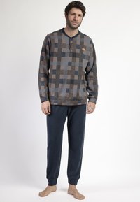 Camisa de manga larga en patrón a cuadros marr�ón, gris y azul con cuello henley. Joggers azul marino con puños elásticos y textura suave.