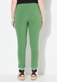 Pantalones verdes elásticos con un diseño ajustado, que cuentan con detalles de encaje en los tobillos. La cinturilla es elástica, lo que proporciona comodidad y flexibilidad.