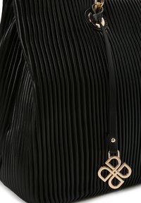 Borsa a tracolla nera in pelle plissettata con superficie texturizzata, accenti in hardware dorato e un ciondolo decorativo con logo attaccato da una tracolla in pelle.