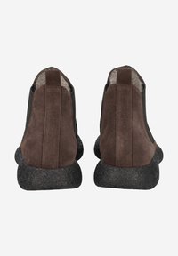 Bottines en cuir suédé marron avec un panneau en cuir noir lisse, des semelles en caoutchouc texturé foncé et une petite languette à l'arrière pour un enfilage facile.
