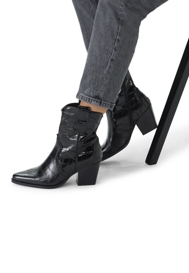 Black ankle boots with a pointed toe, glossy croc-embossed texture, and a chunky heel. Features elastic side panels and a zip closure.